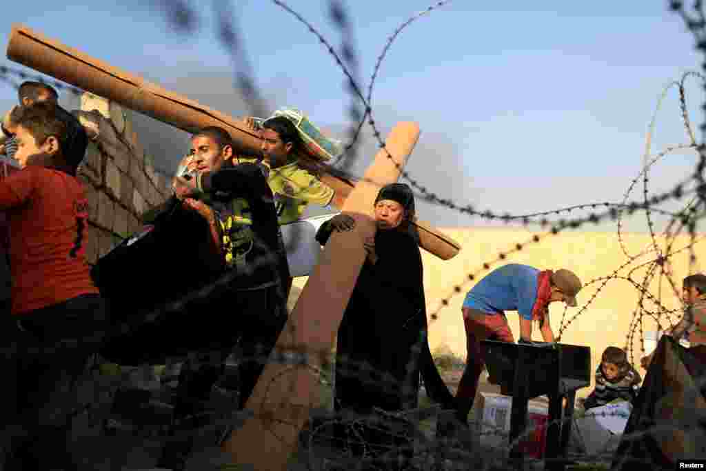 Para pengungsi Irak membawa barang-barang bantuan kemanusiaan di Qayyara, selatan kota Mosul, sementara pasukan Irak menggempur ISIS di Mosul.