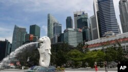 资料照片： 2020年6月30日，人们在新加坡滨海湾地区拍摄鱼尾狮雕像。