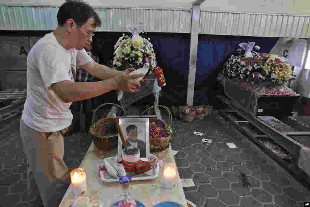 Seorang kerabat memegang merpati dekat peti-peti jenazah korban AirAsia bernomor penerbangan 8501 dalam proses kremasi di Surabaya (8/1). (AP/Trisnadi)