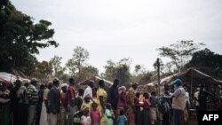FILE - A United Nations High Commissioner for Refugees worker welcomes refugees from the Central African Republic at the entrance of a refugee registration site in Ndu, Bas-Uele Province, Democratic Republic of Congo, Jan. 21, 2021.