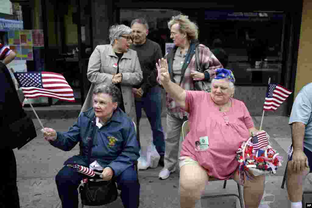 Jane Wick (kiri) dan Mary Ann Chubirka melambaikan bendera saat menyaksikan parade Hari Pahlawan di College Point, New York, 26 Mei 2013. (AP Photo/Seth Wenig)