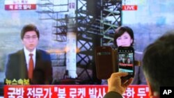 South Korean man uses his smartphone to take a photo of television screen reporting news about North Korea's rocket launch at Seoul Railway Station in Seoul, South Korea, December 12, 2012.