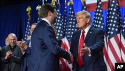 赢得2024年总统选举胜利的共和党候选人、前总统特朗普在佛罗里达州西棕榈滩的夜晚观选会场与他的副总统竞选搭档万斯握手。(2024年11月6日)