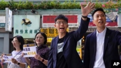 Election winner candidate Kelvin Lam, right, and pro-democracy activist Joshua Wong, second right, wave to people and thank for their support, outside South Horizons Station in Hong Kong, Monday, Nov. 25, 2019. Pro-democracy candidates won nearly…