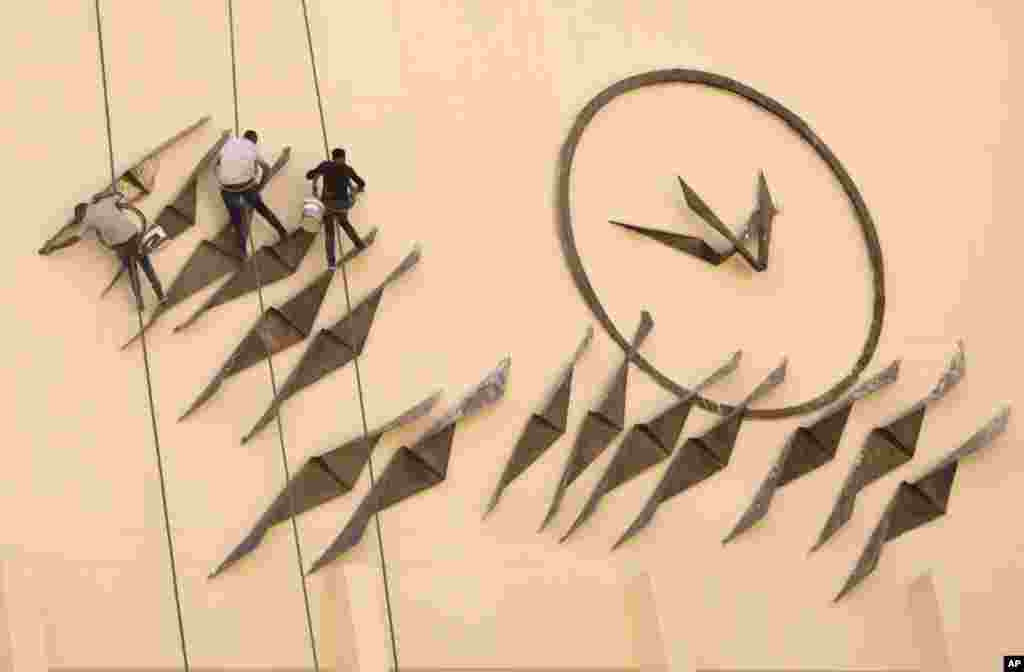 Para pekerja membersihkan sebuah mural/lukisan dinding pada gedung Opera di Kairo, Mesir.