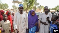 Msichana aliyeachiwa huru na Boko Haram akitembea na baba yake (kushoto) katika eneo la Dapchi Machi 21, 2018.