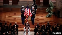 Des membres du clergé et une garde d'honneur militaire portant le cercueil drapé du drapeau partent à la fin des funérailles d'État de l'ancien président George H.W. Bush dans la cathédrale nationale de Washington, le 5 décembre 2018.