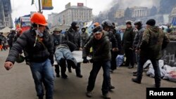 20일 우크라이나 수도 키예프에서 반정부 시위대와 경찰이 또 다시 충돌한 가운데, 시위대가 부상자를 옮기고 있다.