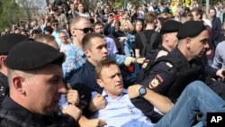 Abaporisi mu Burusiya bateruye uwutavuga rumwe na reta Alexei Navalny, hagati, mu myiyerekano yiyamiriza iyimikwa rya Perezida Vladimir Putin i Moscou, mu Burusniya, itariki 5/05/2018. Thousands of demonstrators denouncing Putin's upcoming inauguration into a fourth term gathered Saturday in the capital's Pushkin Square. (AP Photo)