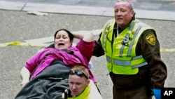 医疗救护人员在波士顿马拉松终点线附近救助一名受伤的女士。 