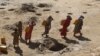 FILE - Women carry jerry cans of water from shallow wells dug from the sand along the Shabelle River bed, which is dry because of drought in Somalia's Shabelle region, March 19, 2016.
