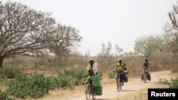 Une femme ramène de l'eau dans des bidons sur son vélo en direction du village de Bagare, dans la province de Passore, nord du Burkina Faso, le 30 mars 2016.