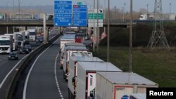 FILE - Trucks queue on the motorway as French Customs Officers increase controls on transported goods to protest the lack of resources as the Brexit date approaches, in Calais, France, March 13, 2019.