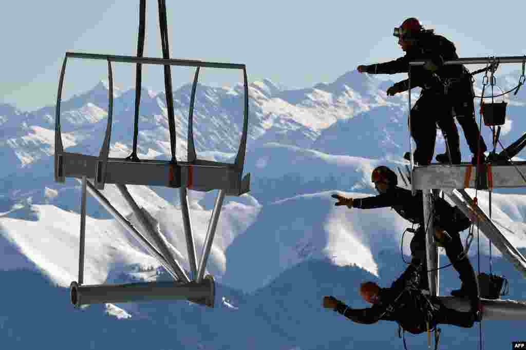 Technicians reach out to catch a piece of a metal structure during the installation of a 12-meter-long platform at the top of the Pic du Midi, one of France&#39;s tallest mountains, in Bagneres-de-Bigorre.