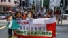 Pro-democracy demonstrators hold up a banner and portraits of jailed Chinese civil rights activists, lawyers and legal activists as they march to the Chinese liaison office in Hong Kong, Thursday, June 25, 2020. The banner read "One-party…