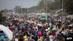 People carry bags of food on their heads during a mass looting of a warehouse with COVID-19 food palliatives that were not given during lockdown to relieve people of hunger, in Abuja, Nigeria, Oct. 26, 2020.