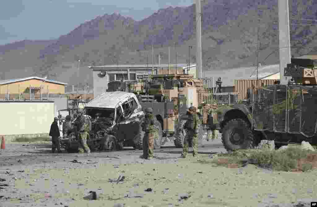 U.S. soldiers remove a destroyed vehicle from the site of a suicide attack in Kabul, Afghanistan, Oct. 13, 2014.