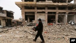 A man carries his belongings through a street destroyed in recent bombings by the Syrian government forces in the town of Sarmin, in Idblib province, Syria, Feb. 7, 2020.