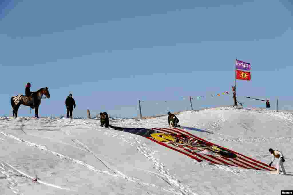 ជនជាតិ​ដើម​អាមេរិកាំង​វ័យក្មេង​ម្នាក់​អង្គុយ​លើ​ខ្នង​សេះ ហើយ​មើល​ទាហាន​ជើងចាស់​ត្រដាង​ទង់ជាតិ​ជិត​ជំរុំ Oceti Sakowin ខណៈ​ដែល​ &laquo;ក្រុម​អ្នក​ការពារ​ទឹក&raquo; បន្ត​ធ្វើ​បាតុកម្ម​ប្រឆាំង​នឹង​គម្រោង​ដំណើរការ​ការ​បូម​ប្រេង​របស់​ក្រុមហ៊ុន Dakota Access ជិត​តំបន់​អភិរក្ស​ថ្ម​សិលា​ជនជាតិ​ដើម​ឥណ្ឌា Standing Rock Indian Reservation ជិត​ក្រុង Cannon Ball រដ្ឋ North Dakota កាល​ពី​ថ្ងៃ​ទី​០៤ ខែ​ធ្នូ ឆ្នាំ​២០១៦។&nbsp;