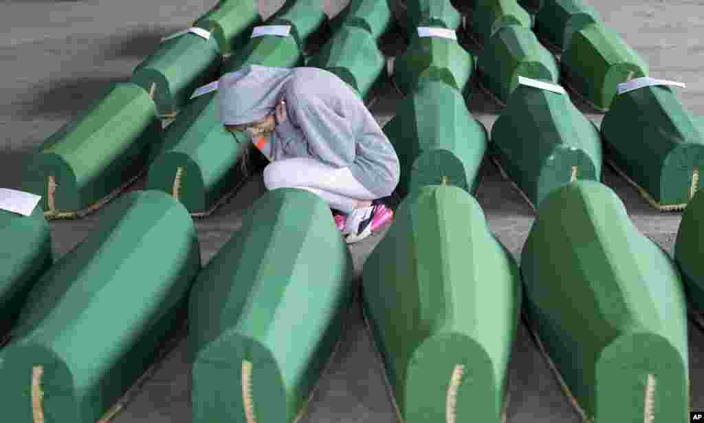 A girl inspects coffins prepared for burial, in Potocari near Srebrenica, Bosnia. The remains of 33 victims of Srebrenica massacre will be buried on July 11, 2019, 24 years after Serb troops overran the eastern Bosnian Muslim enclave of Srebrenica and executed some 8,000 Muslim men and boys.