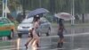 Women walk with umbrellas during torrential rains, August 5, 2020, in Pyongyang.