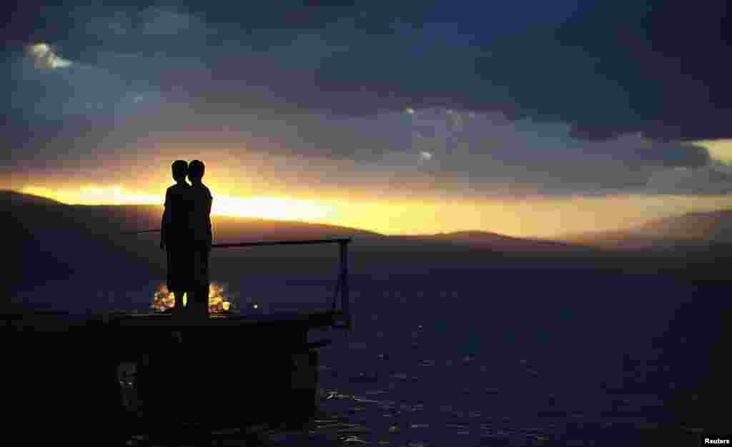 Dua anak memancing di Danau Ohrid, Trpejica, Macedonia saat malam hari.