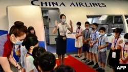FILE - Flight attendants from Taiwan's China Airlines stage a 'flight to nowhere' event for children, at the China Airlines' campus in Taoyuan City, Taiwan, Aug. 8, 2020.