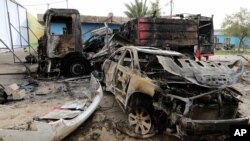 Bangkai mobil-mobil yang terbakar sehari setelah serangkaian bom meledak di sebelah timur Baghdad, Irak, Sabtu (26/4). (AP/Karim Kadim)