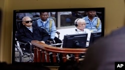 Khieu Samphan, second from right, former Khmer Rouge head of state, and Noun Chea, left, who was the Khmer Rouge's chief ideologist and No. 2 leader, is seen on a screen at the court's press center of the U.N.-backed war crimes tribunal in Phnom Penh, file photo. 