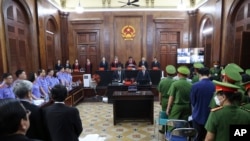 People stand before Vietnamese real estate tycoon Truong My Lan enters a courtroom in Ho Chi Minh City, Vietnam on Tuesday, March 5, 2024. (Phan Thanh Vu/VNA via AP)