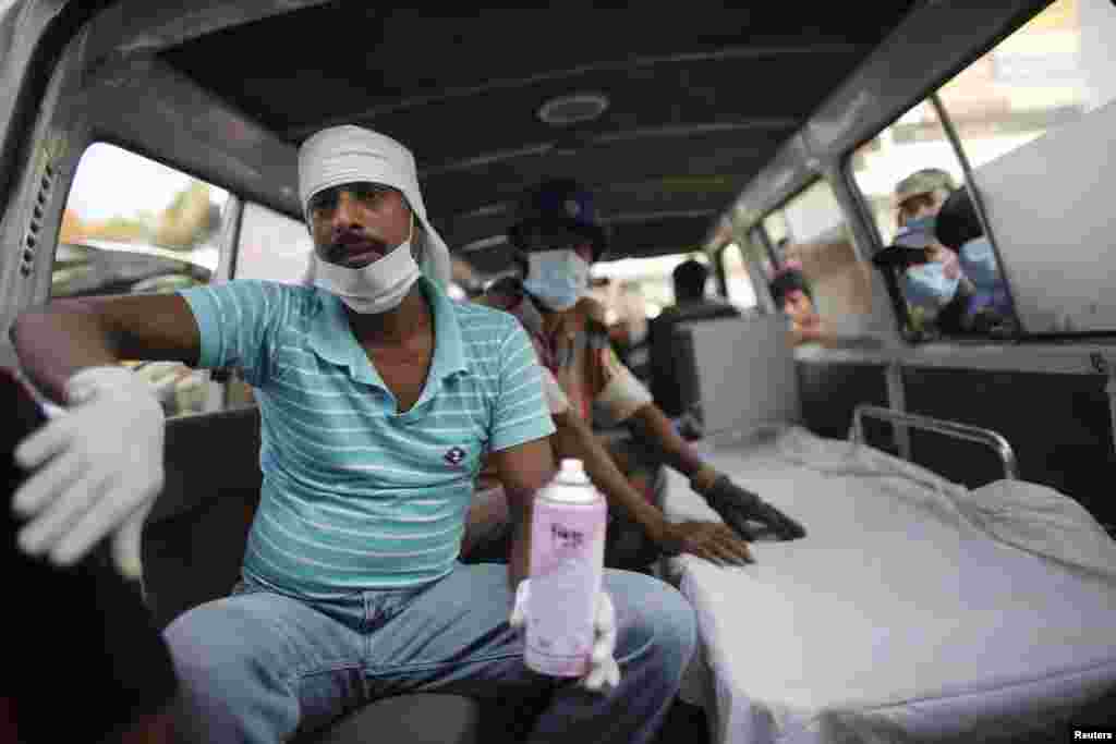 2013年4月26日，一名救援人员坐在救护车内，等待把受伤的服装厂工人送往医院。孟加拉国达卡城外的萨瓦镇一家服装厂的大楼24日倒塌。