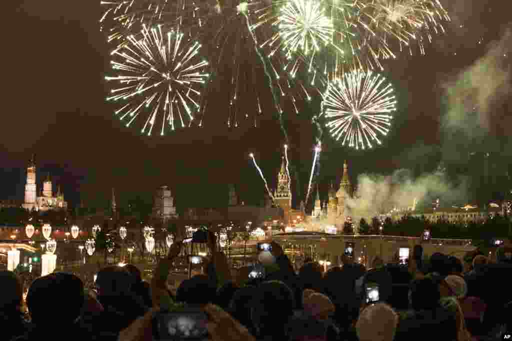 People take pictures as fireworks explode over the Kremlin, during New Year celebrations in Moscow, Russia, Monday, Jan. 1, 2018. New Year is Russia&#39;s major gift-giving holiday. (AP Photo/Denis Tyrin)