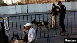 A street vendor smokes a cigarette as police officers walk past, next to the boarded Zocalo Square outside the National Palace, where U.S. President Barack Obama and his Mexican counterpart Enrique Pena Nieto will meet Thursday in Mexico City, May 2, 2013