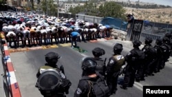 Warga Palestina melakukan ibadah sembahyang Jumat pertama dalam bulan Ramadan sementara polisi Israel berjaga di wilayah Wadi al-Joz, Yerusalem Timur (4/7).