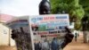 A resident reads a daily newspaper on April 27, 2016 reporting on the arrival and swearing-in of rebel leader Riek Machar in Juba, South Sudan, a day after his return. 