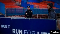 FILE - A NYPD officer stands guard during the ceremonial painting of the New York City Marathon blue line at Central Park in New York.