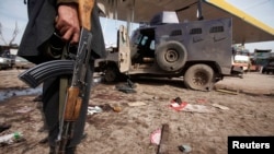 Seorang petugas keamanan berdiri di dekat kendaraan yang hancur akibat ledakan bom bunuh diri di dekat Peshawar (14/3). Sedikitnya tujuh orang dilaporkan tewas dan 35 lainnya terluka dalam serangan yang menarget panser militer ini.
