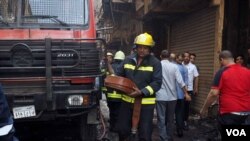 A fireman folds a fire extinguisher tube after his truck runs out of water in a busy, commercial area downtown Cairo on May 11, 2016. (VOA /Hamada Elrasam)
