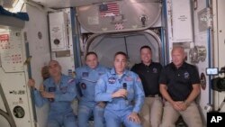 This photo provided by NASA shows Bob Behnken and Doug Hurley, far right, joining the the crew at the International Space Station, after the SpaceX Dragon capsule pulled up to the station and docked Sunday, May 31, 2020.