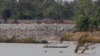 FILE - In this June 20, 2016 file photo, a fishing boat passes near a construction site of the Don Sahong dam, near Cambodia-Laos borders, in Preah Romkel village, Stung Treng province, northeast of Phnom Penh, Cambodia. 