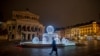 A man passes by the illuminated fountain in front of the Old Opera in Frankfurt, Germany, Dec. 10, 2020.