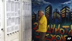 Seorang warga Yunani tengah memeriksa daftar pilihan di salah satu TPS di Athena (17/6). Yunani menyelenggarakan pemilu ulang yang dapat menentukan arah kebijakan negara yang terlilit hutang di Zona Euro itu.