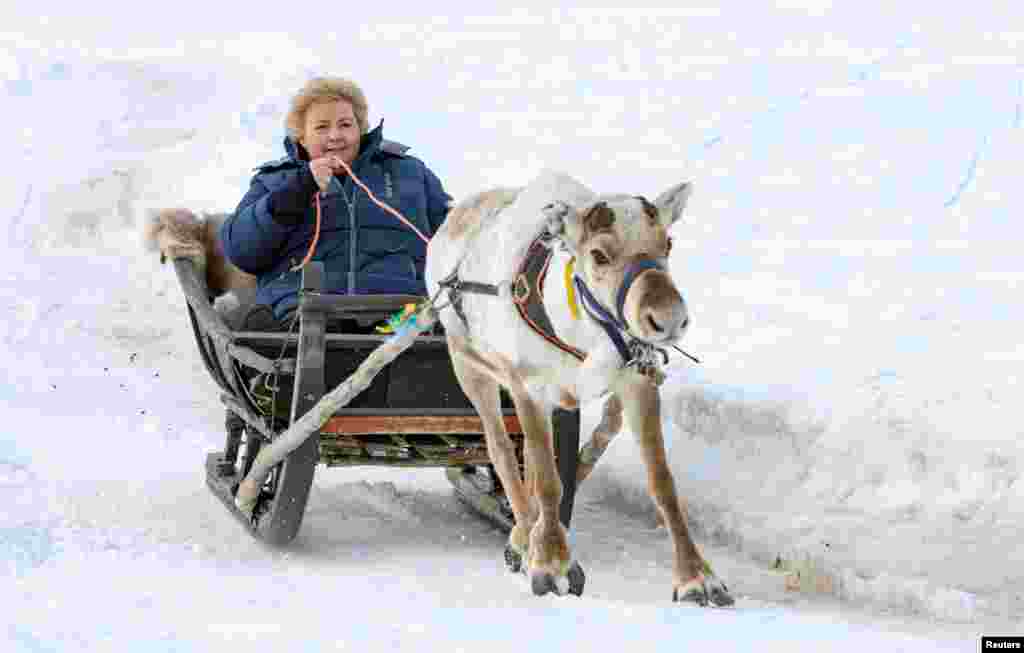 Norwegian Prime Minister Erna Solberg rides on a deer sledge during her visit in Alta.