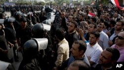 防暴警察守卫在开罗的埃及最高法院外应对呼喊口号的穆尔西总统支持者