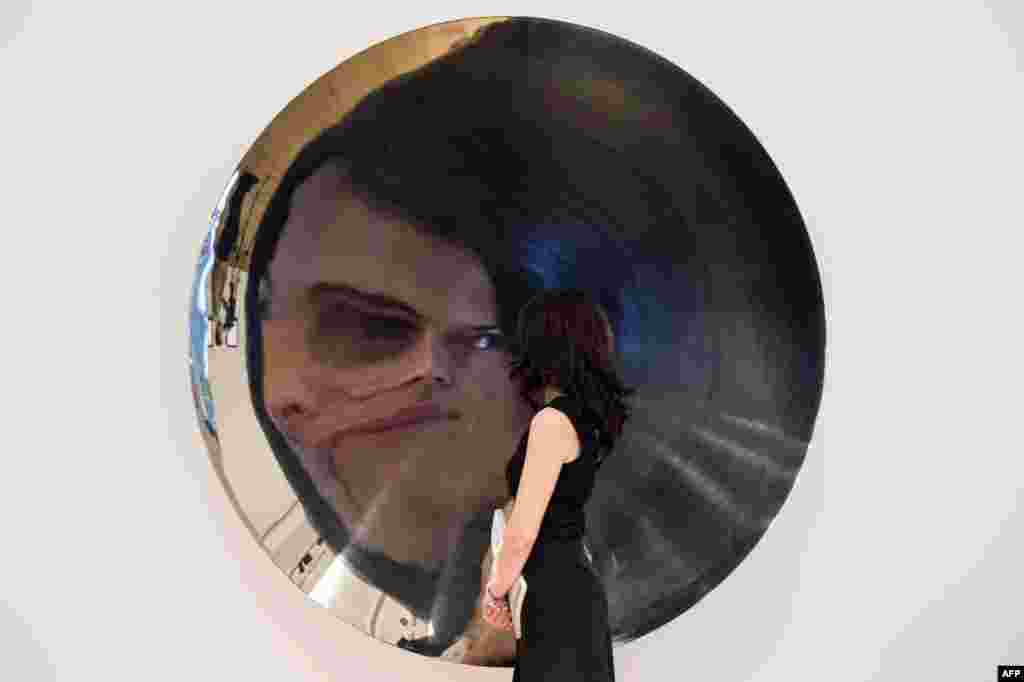 An employee of Bonham&#39;s auction house examines an untitled stainless steel sculpture by Anish Kapoor during a press preview in London ahead of the Post-War and Contemporary Art Sale on July 2. The sculpture&#39;s value is estimated to be between $765,000-$1,105,000 USD. 