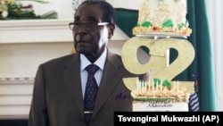 FILE: Zimbabwean President Robert Mugabe stands next to his Birthday cake at State House in Harare, Monday, Feb. 22, 2016.
