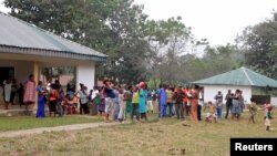 FILE - A still image taken from a video shot on Dec. 9, 2017, shows Cameroonian refugees standing outside a center in Agbokim Waterfalls village, Nigeria, near the country's border with Cameroon.