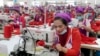 Garment workers sew clothes in a factory as they wait for visit by Prime Minister Hun Sen outside of Phnom Penh, Cambodia, Wednesday, Aug. 30, 2017. 