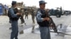 Afghan policemen stand guard as two US soldiers (C) arrive at the site of a twin suicide attack on the NATO's Kandahar Air Base, June 6, 2012.