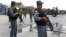 Afghan policemen stand guard as two US soldiers (C) arrive at the site of a twin suicide attack on the NATO's Kandahar Air Base, June 6, 2012.